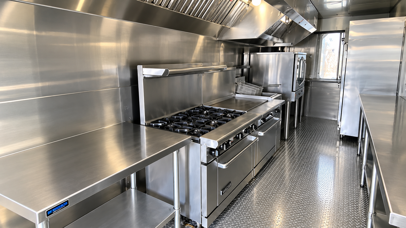 Stainless cooking line, work tables, and hood inside a mobile kitchen